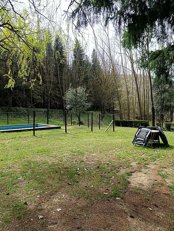 La piscina tancada amb la tanca de seguretat i les gandules plegades al jardí