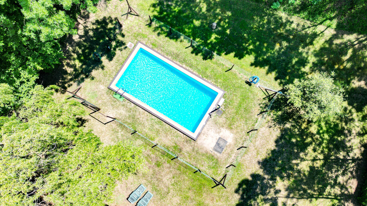 Piscina exterior de Mas Vilarmau rodeada de césped y bosque, vista aérea de dron