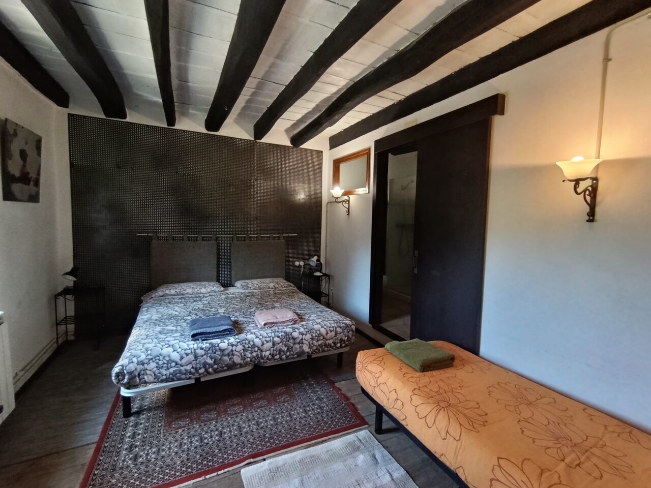 La habitación Hierro, con el cabecero de hierro perforado sobre la pared oscura