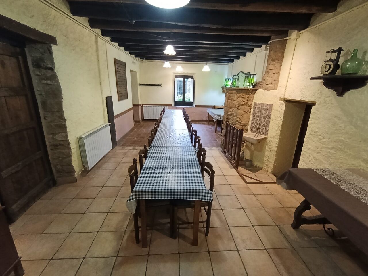 La mesa larga del comedor puesta de lado a lado de la sala, bajo las vigas de madera