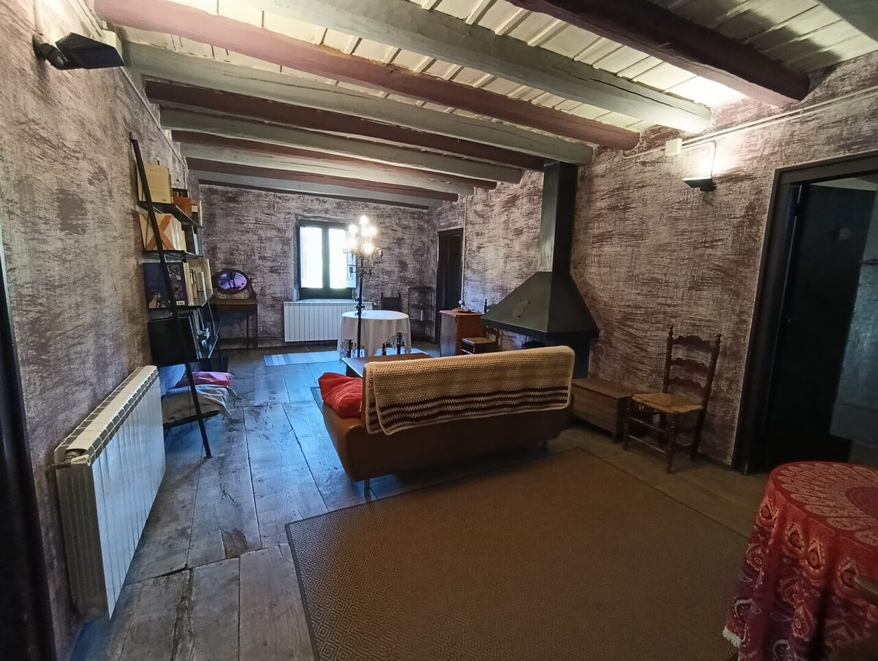 La sala del medio, con la librería, el sofá, la chimenea y el suelo de madera